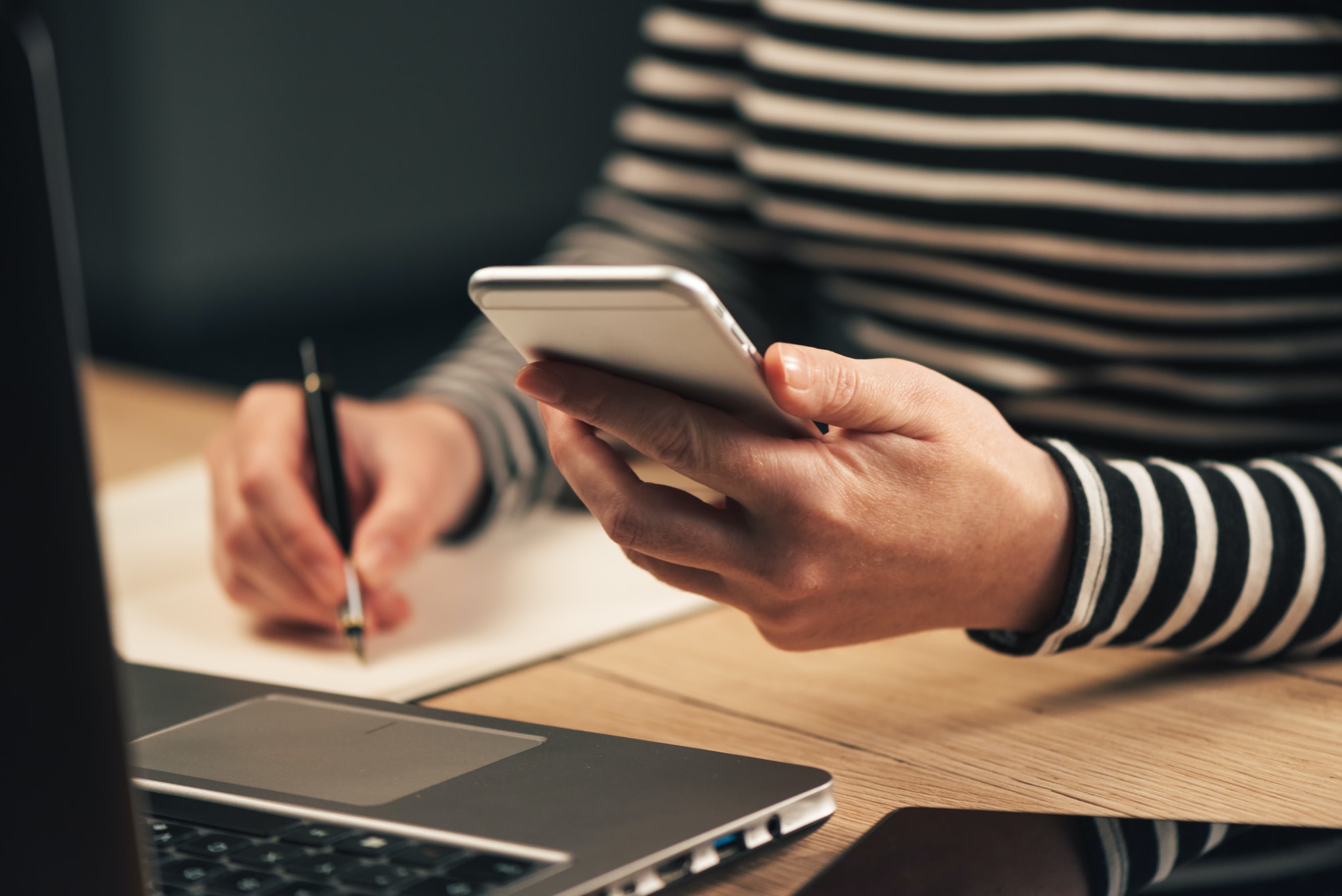Woman writing contact list from phone into business agenda